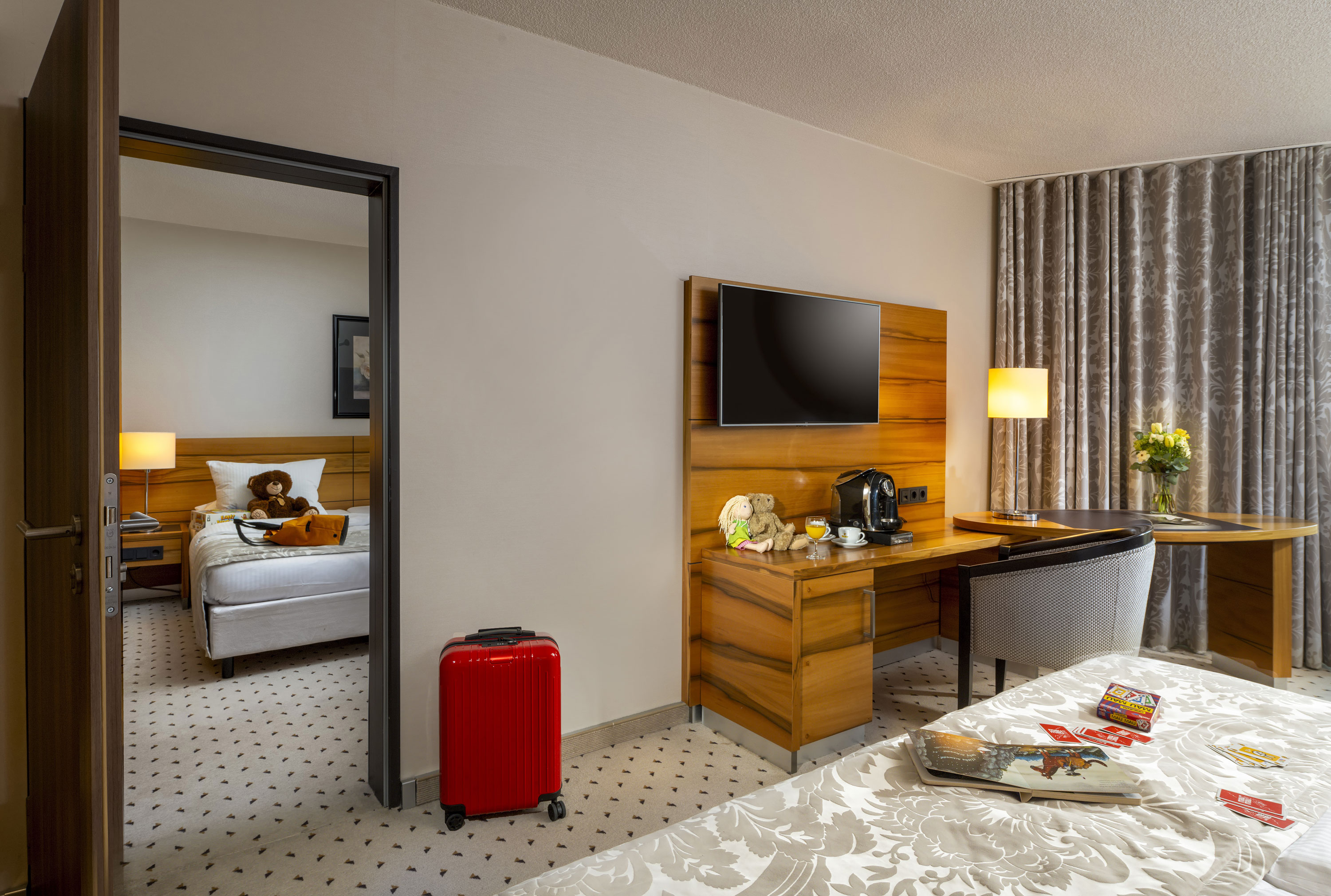 Comfort Family room Family room at Maritim Hotel Bad Homburg with separate kids' room, teddy bears, and red suitcase.